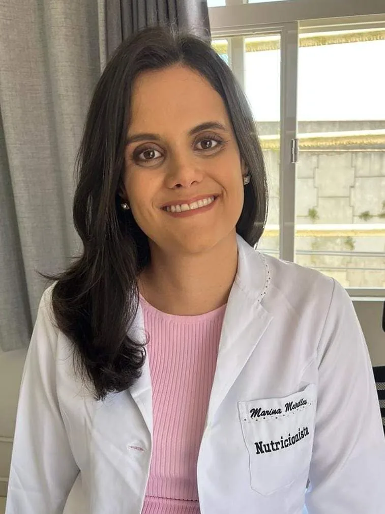 Marina Meirelles de jaleco, sorrindo, no consultório